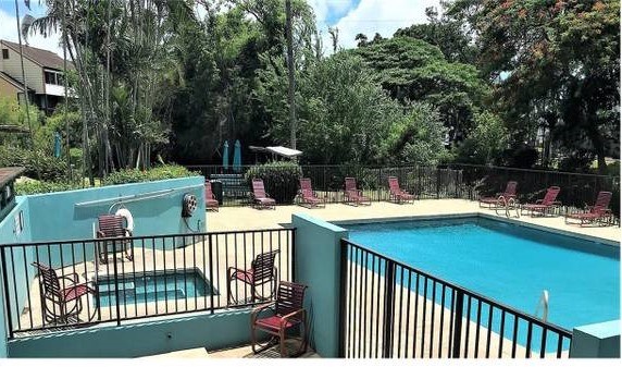 A pool with a hot tub and chairs on a balcony.