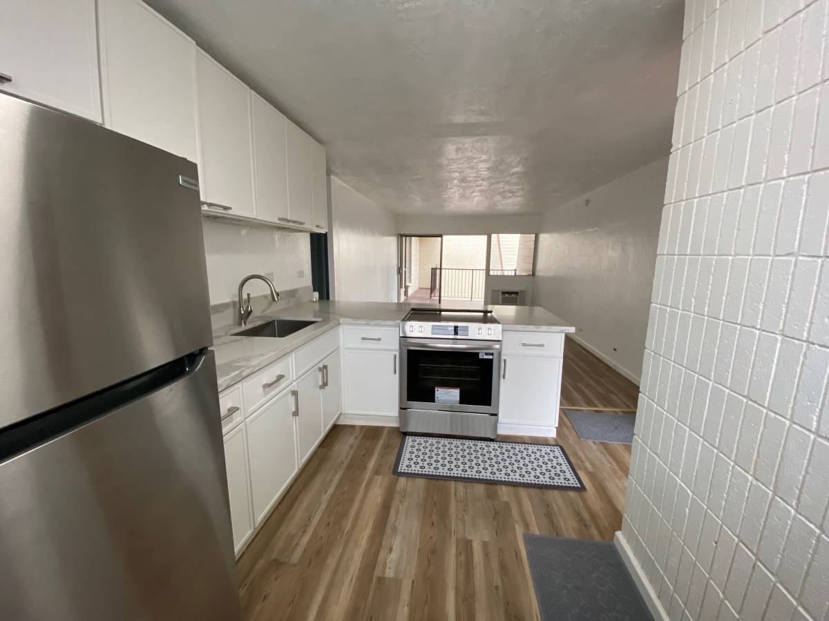 A kitchen with white cabinets and a stainless steel refrigerator.