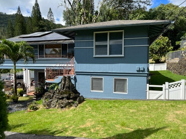 A blue house with a white fence and a rock in front.