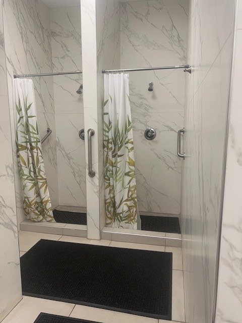 A white marble bathroom with a glass shower door.