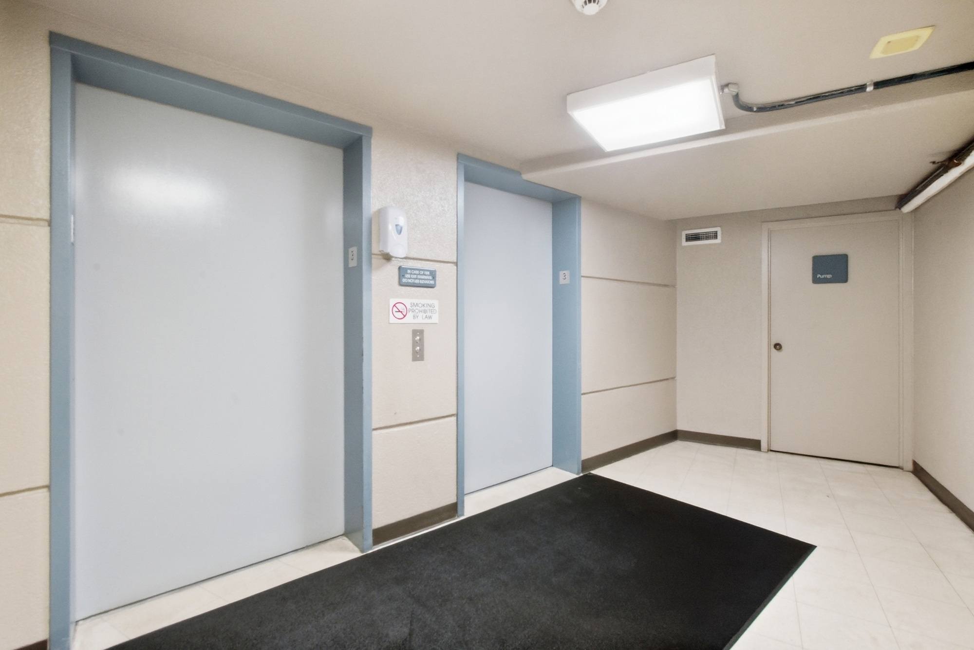 A hallway with a black mat in the middle and doors on both sides.