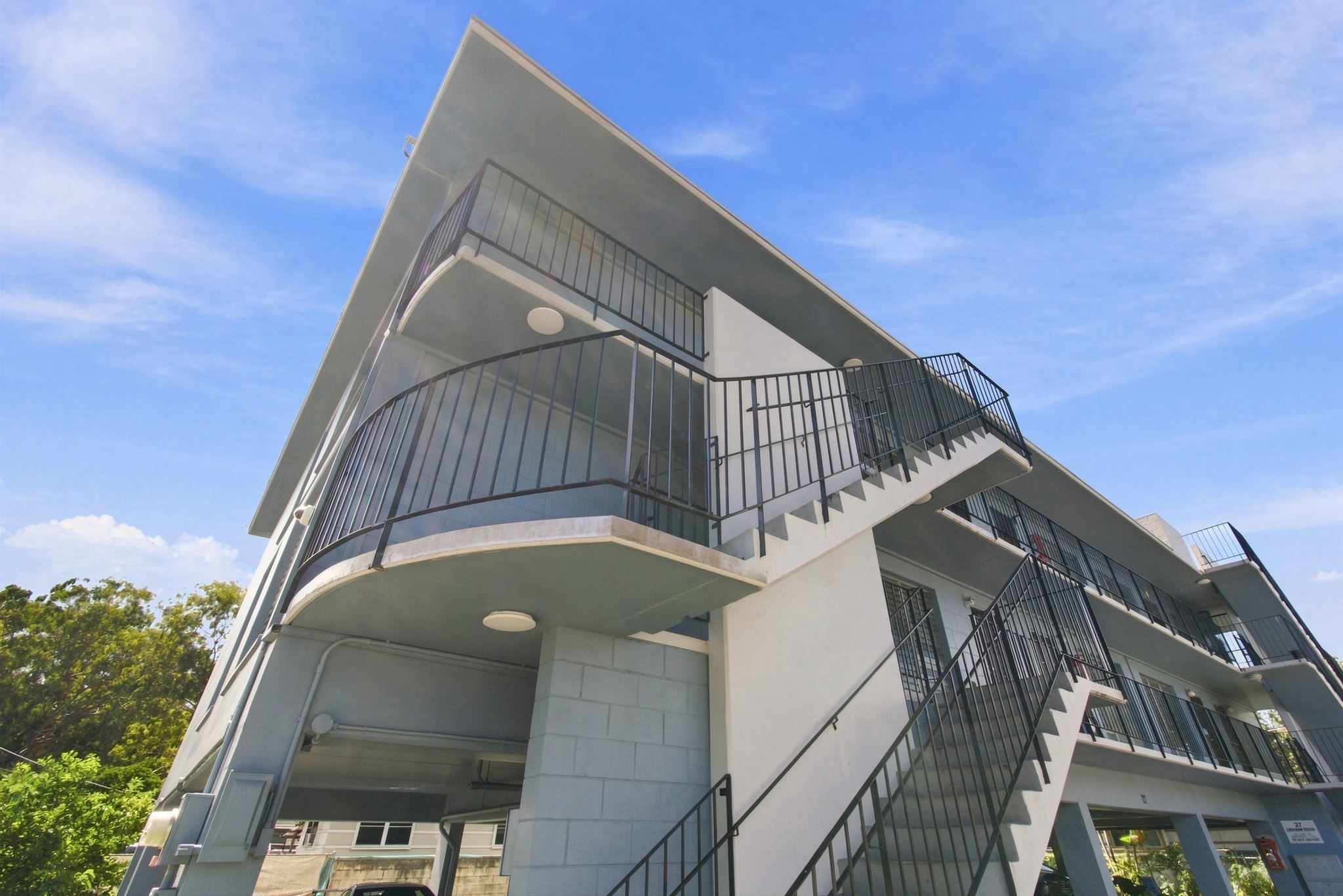 A modern building with a white facade and black railings.