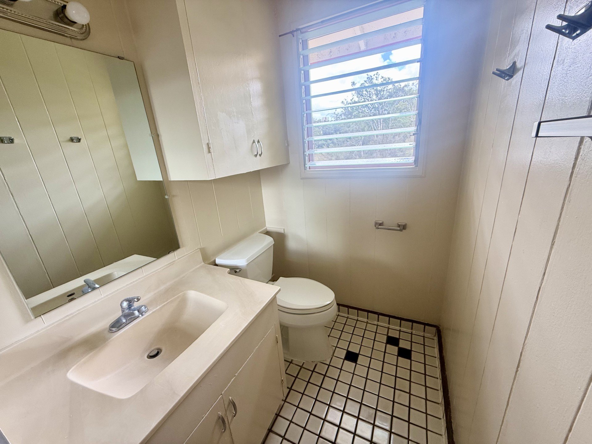 A bathroom with a sink, toilet, and a window.