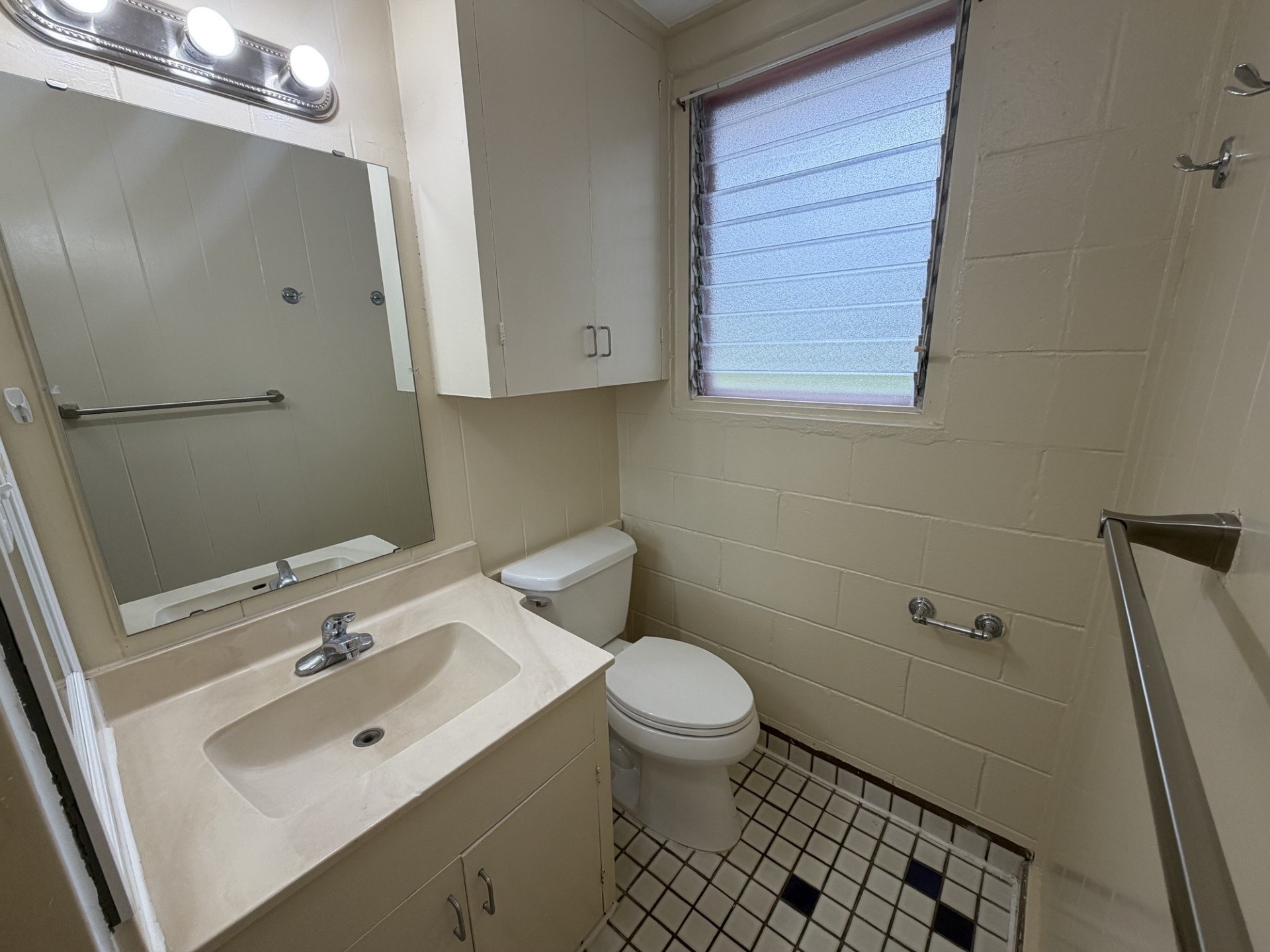 A bathroom with a sink, toilet, and a window.