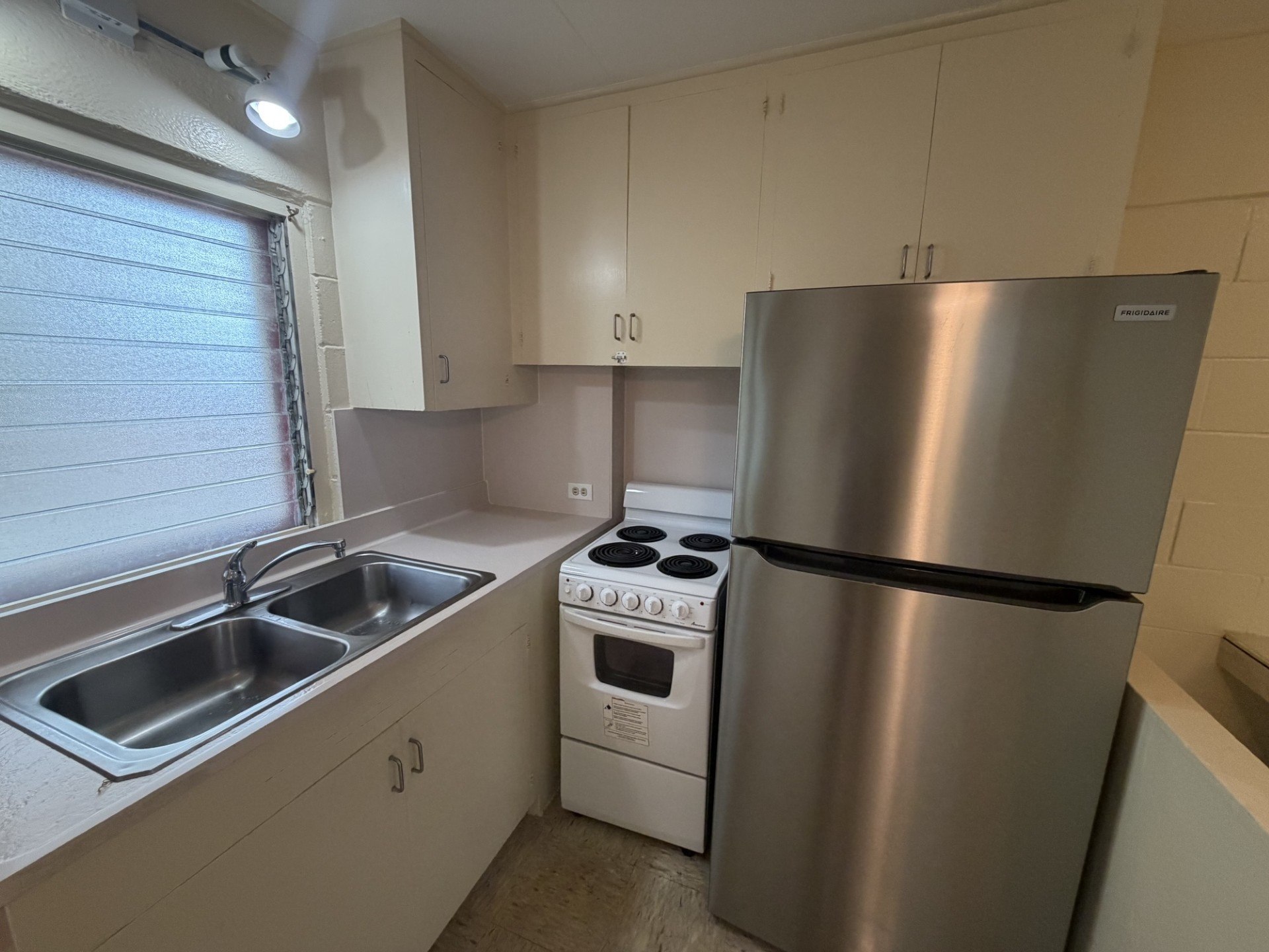 A kitchen with a stainless steel refrigerator, oven, and sink.