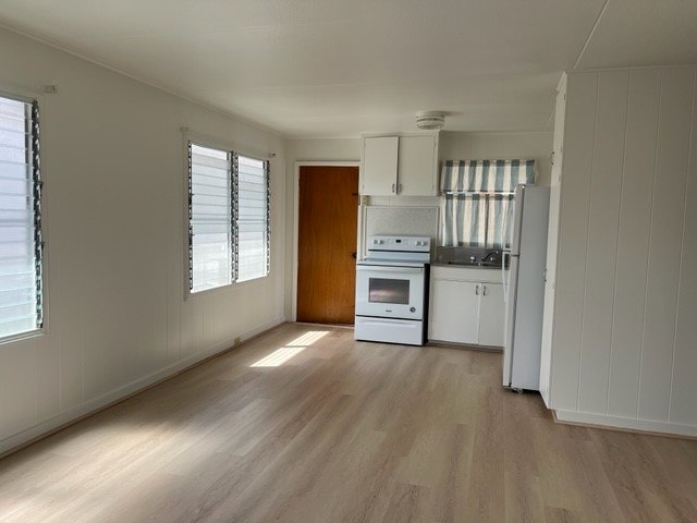 A kitchen with white appliances and wooden floors.