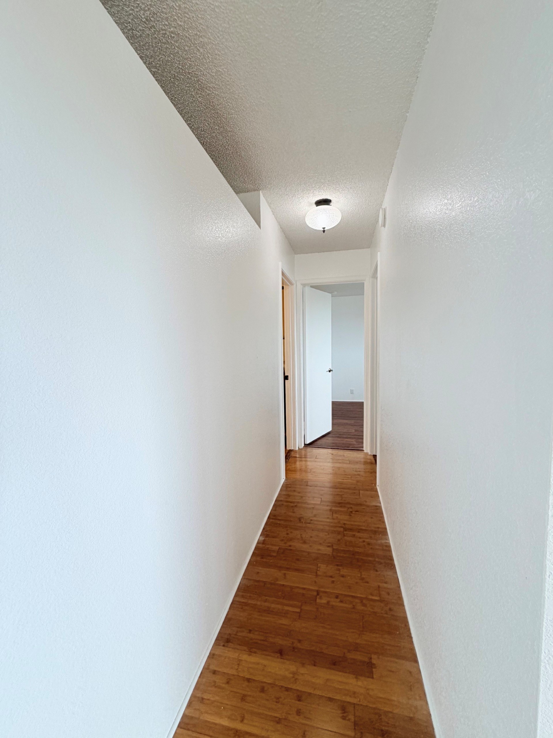 A long hallway with wood floors and white walls.