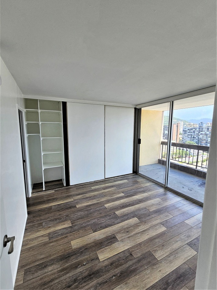 an empty room with a wooden floor and a balcony with a view of the city