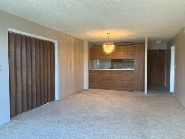 A room with a carpeted floor and a chandelier hanging from the ceiling.