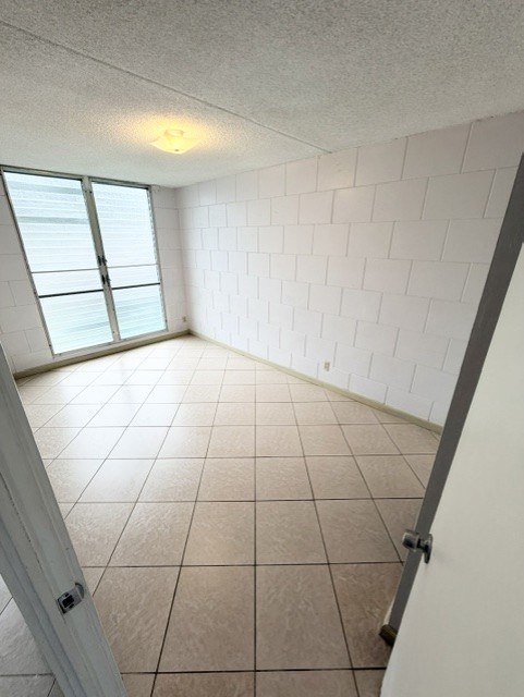 A room with white tiled walls and floor, a window, and a door.
