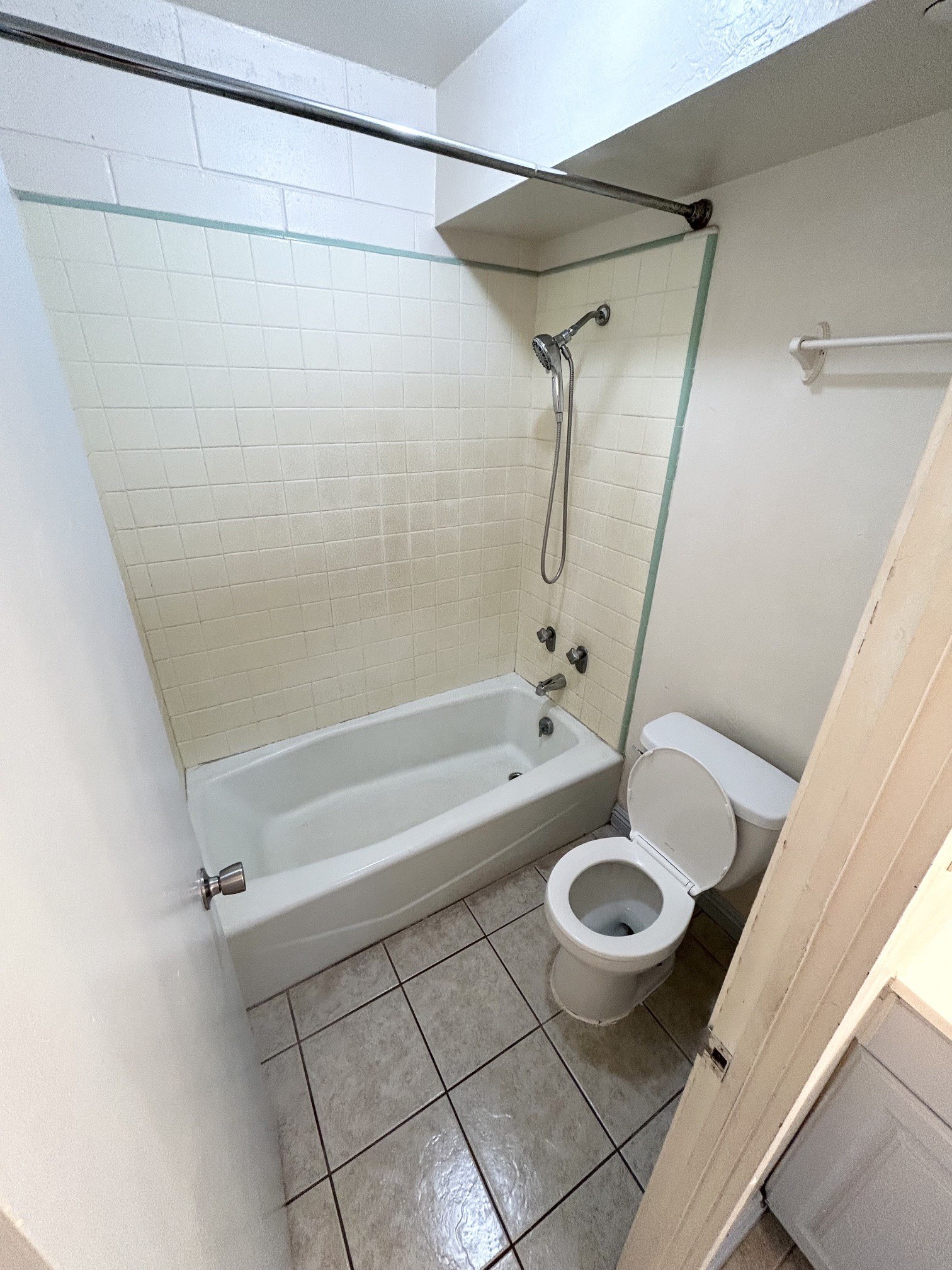 A white toilet sits in a bathroom next to a bathtub.