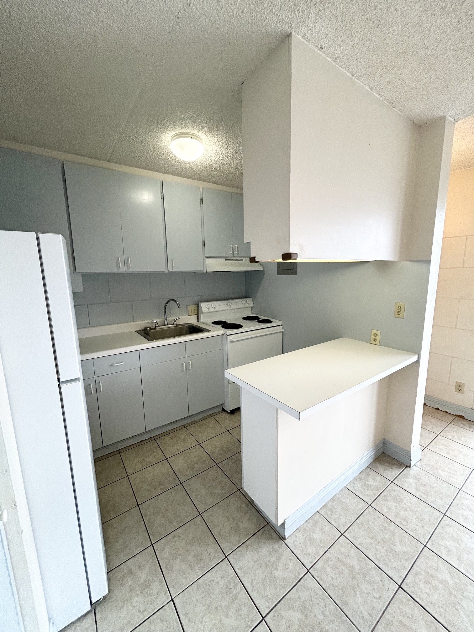 A kitchen with white cabinets and a white refrigerator.