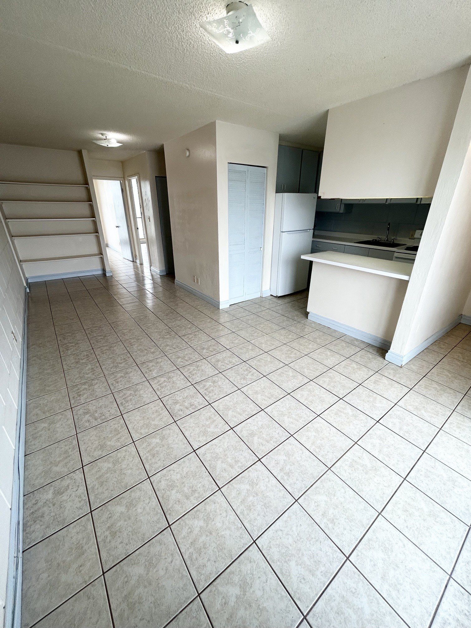 A kitchen area with a refrigerator, sink, and cabinets.