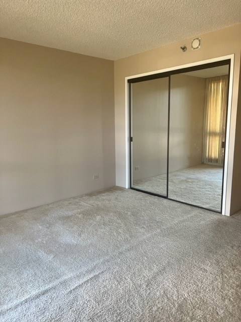 A bedroom with a carpeted floor and a sliding glass door leading to another room.