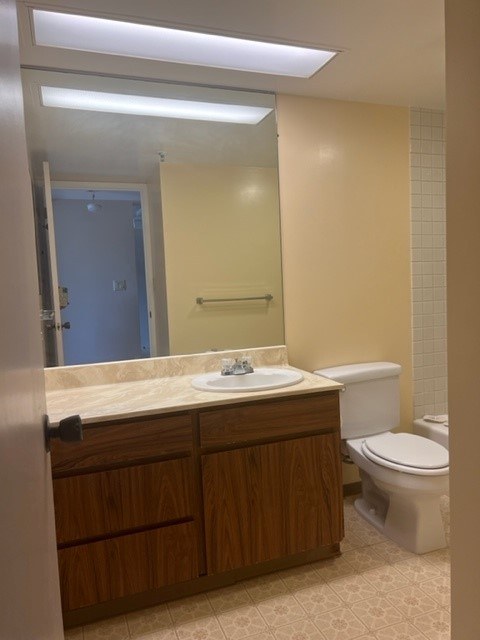 A bathroom with a toilet, sink, and mirror.