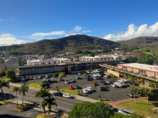 A parking lot with cars and a mountain in the background.