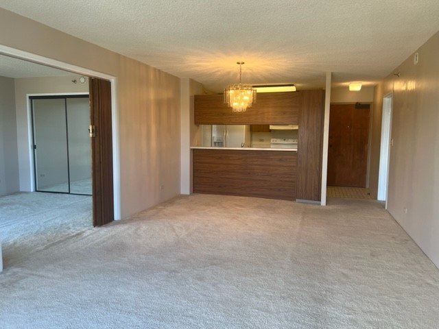 A room with a carpeted floor and a chandelier hanging from the ceiling.