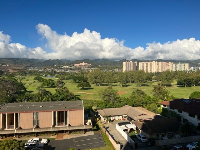 A large building with a red roof is in the foreground of a scenic landscape.
