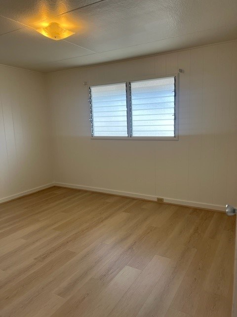 A room with wooden flooring and a window with blinds.