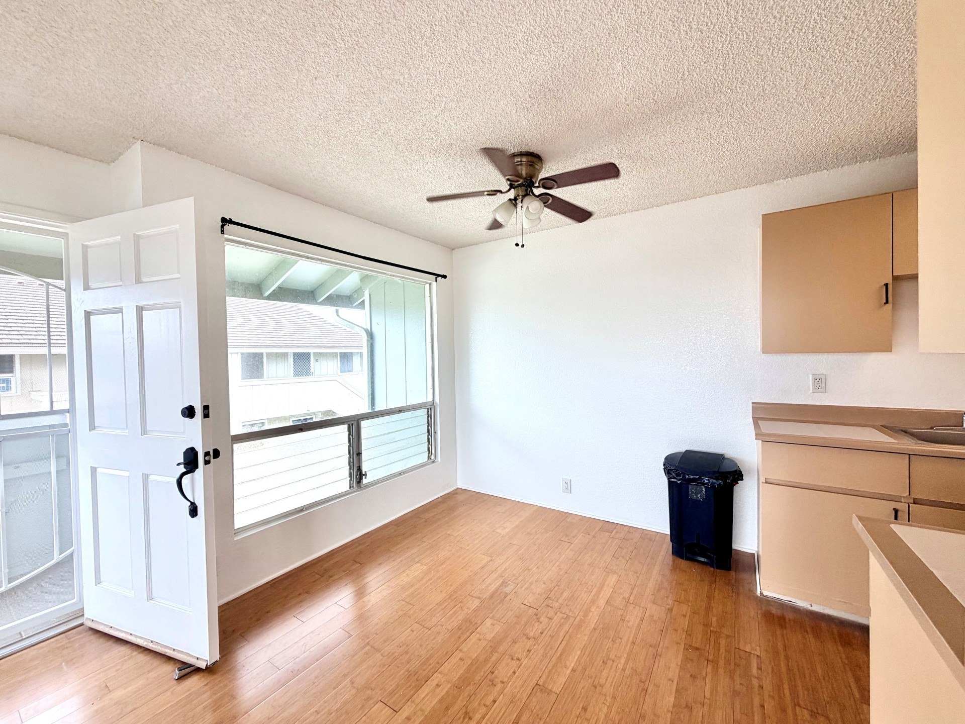 A room with a ceiling fan and a door leading to a balcony.