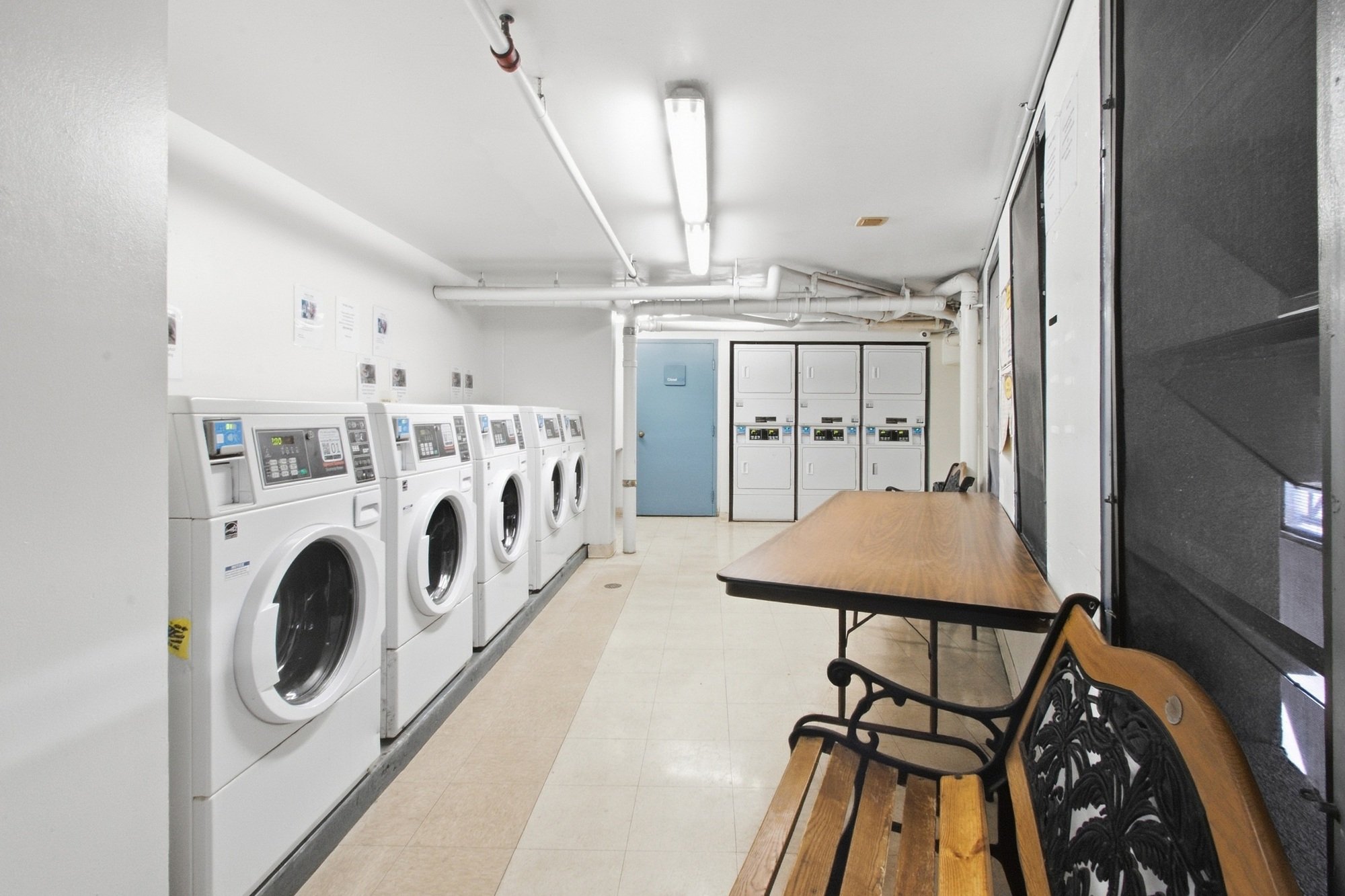 A laundromat with a row of washing machines and a table.