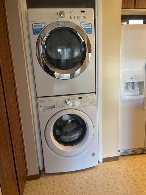 A white washing machine with a dryer on top is in a room.
