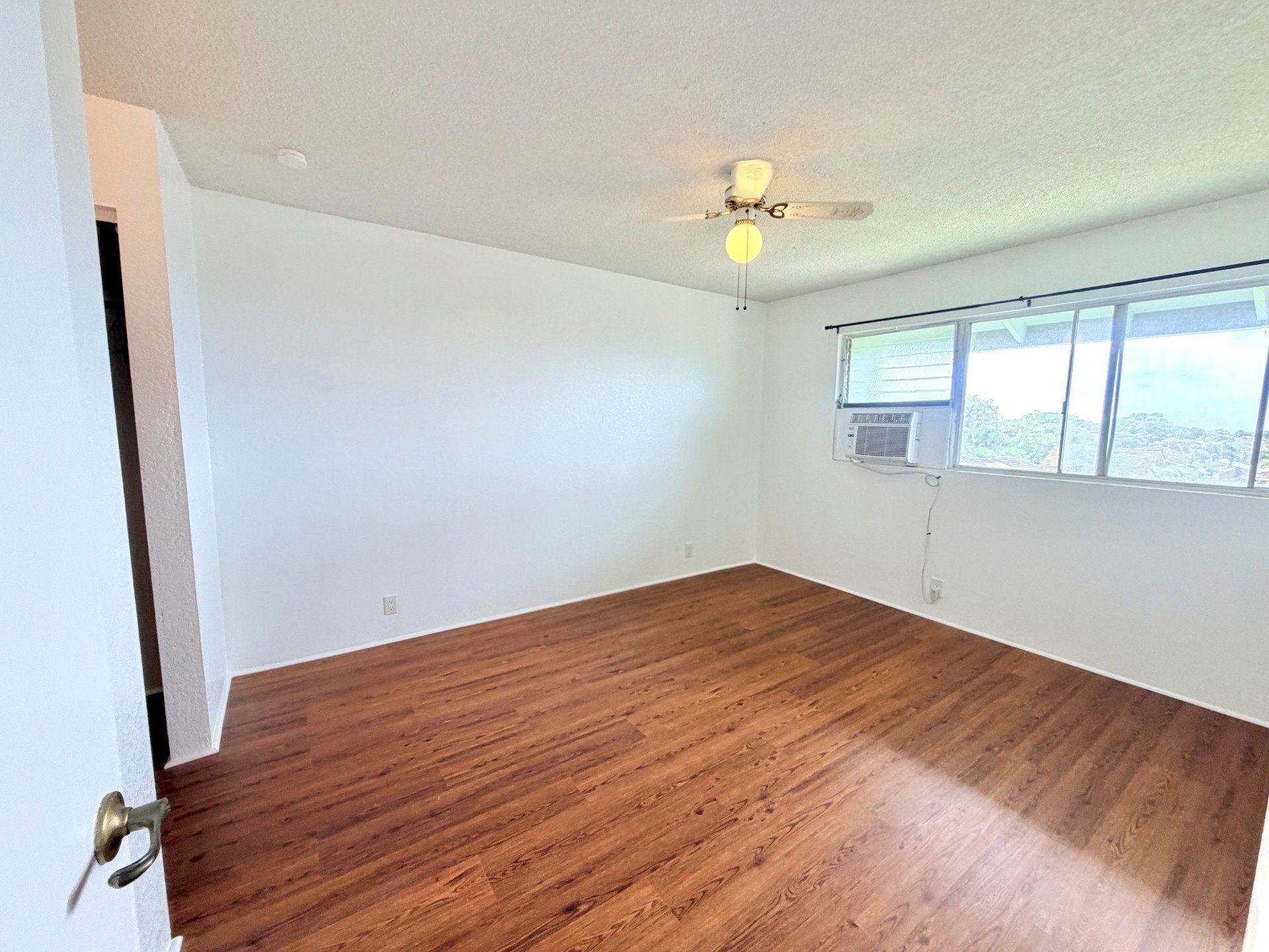 A room with wooden flooring and a ceiling fan.