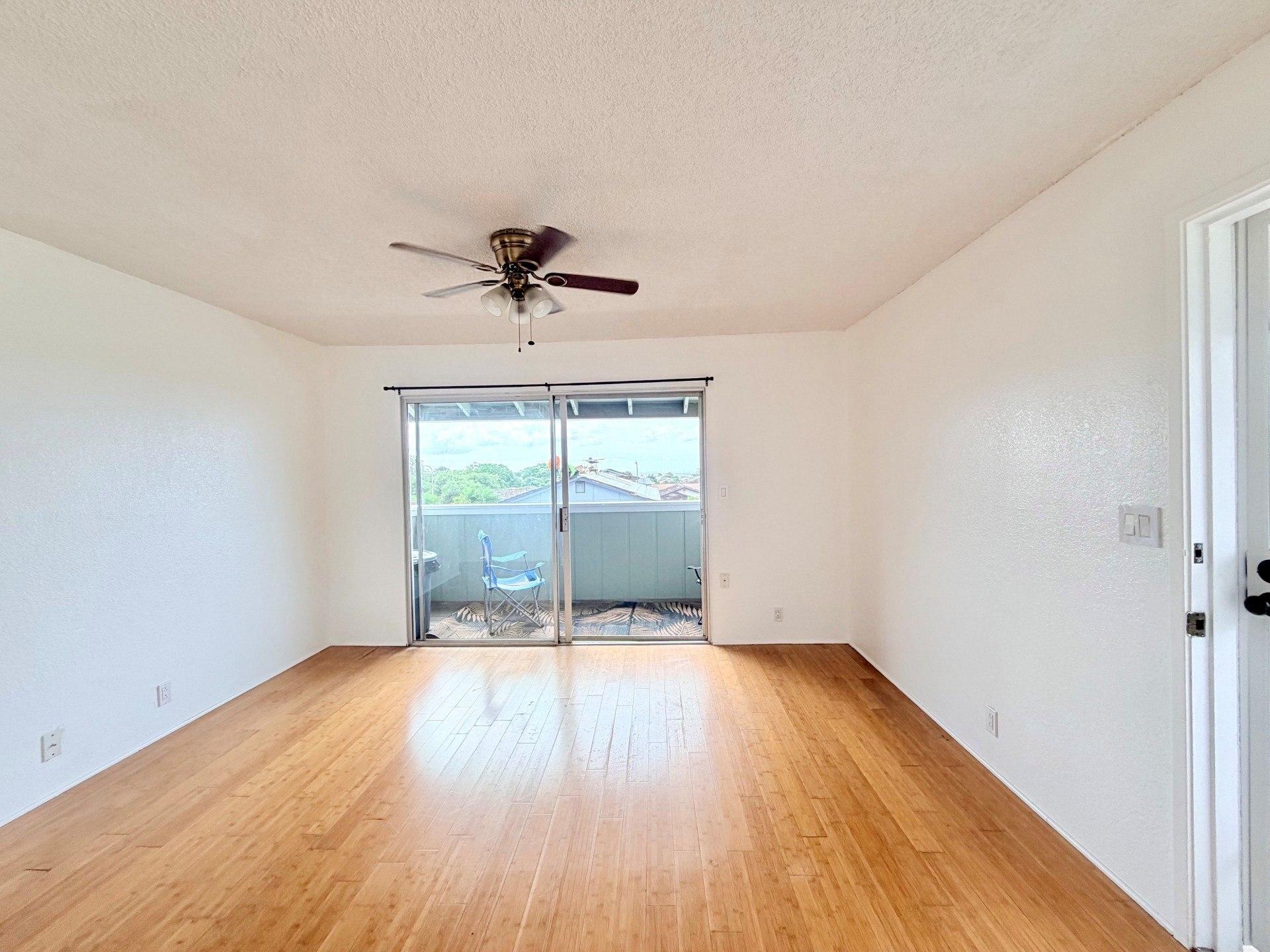 A room with a ceiling fan and sliding glass doors.