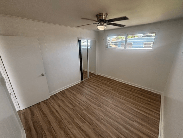 A room with a ceiling fan and sliding glass doors.