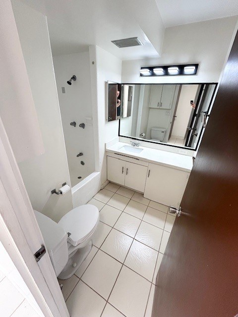 A white toilet in a small bathroom with a mirror above a sink.