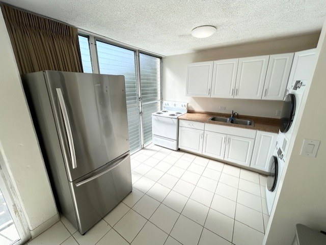 A modern kitchen with a stainless steel refrigerator and white cabinets.