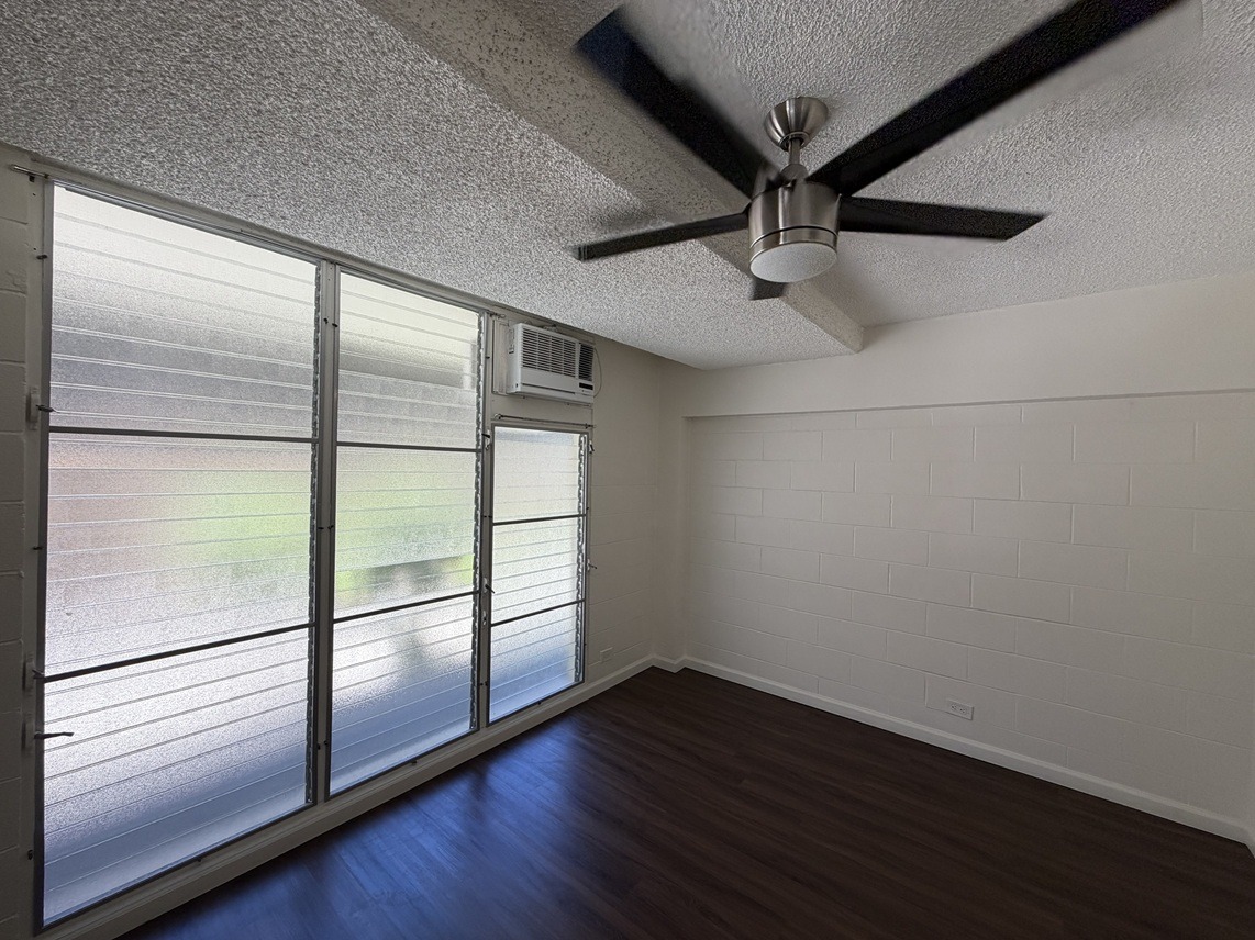 A room with a ceiling fan and sliding glass doors.