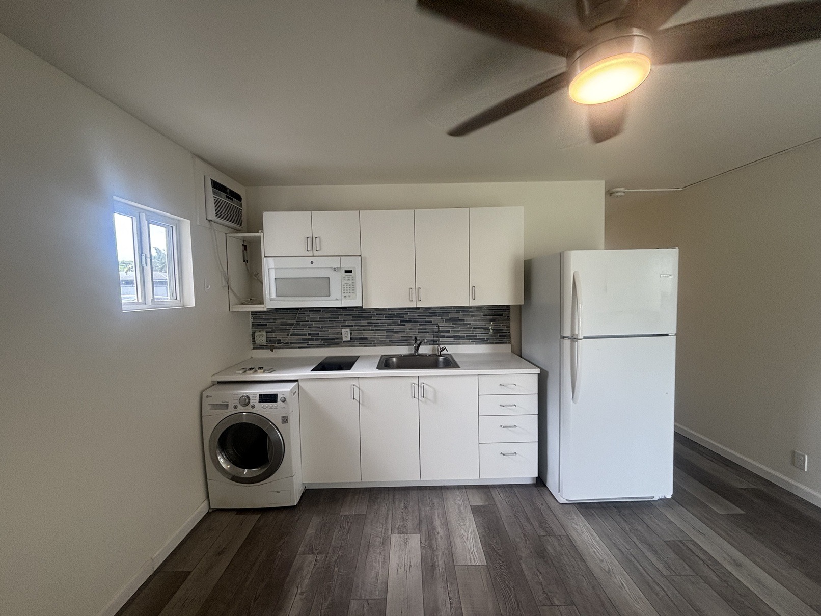 A kitchen with white appliances and wooden floors.