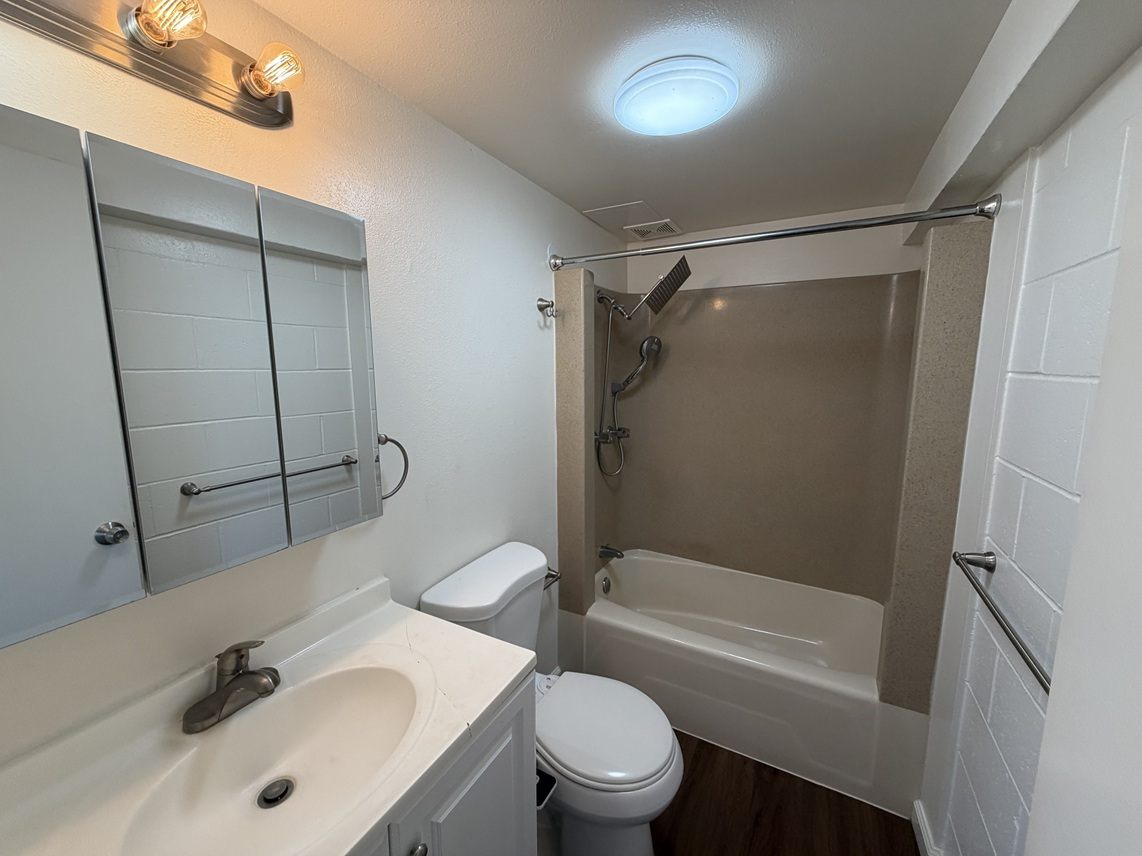 A bathroom with a white sink, toilet, and bathtub.