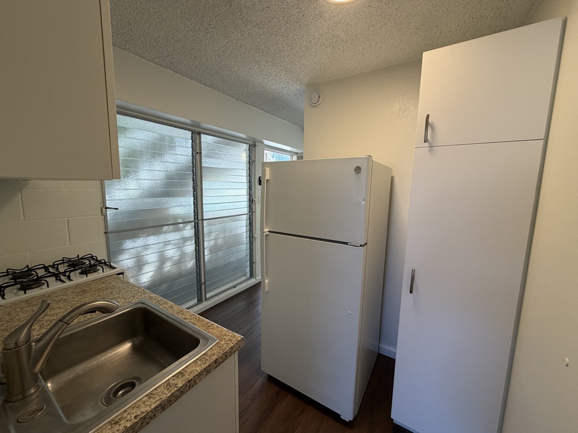 A kitchen with a sink, stove, and two refrigerators.