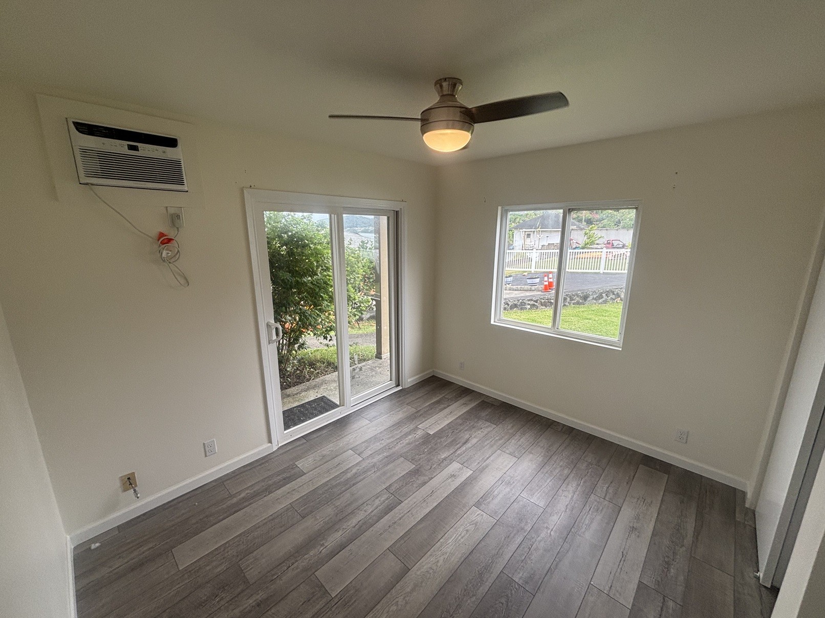 A room with a ceiling fan and sliding glass doors.
