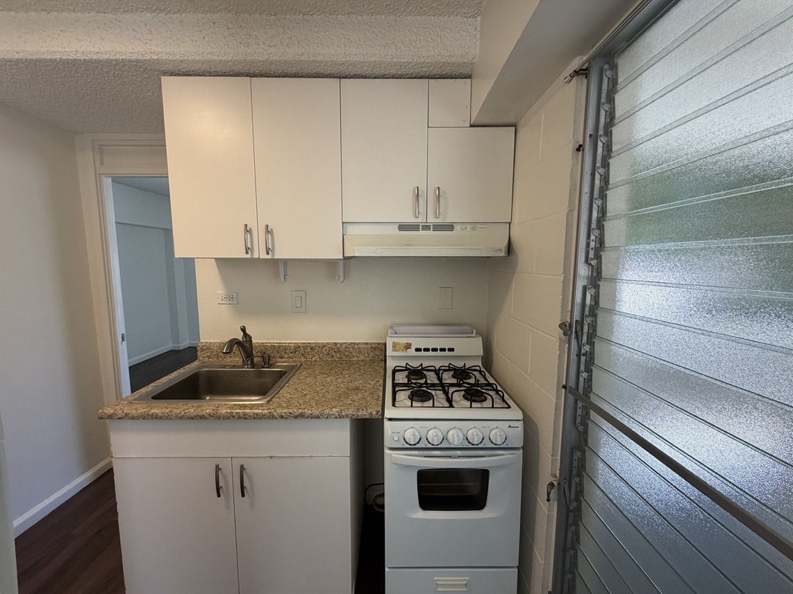A small kitchen with a white stove and cabinets.