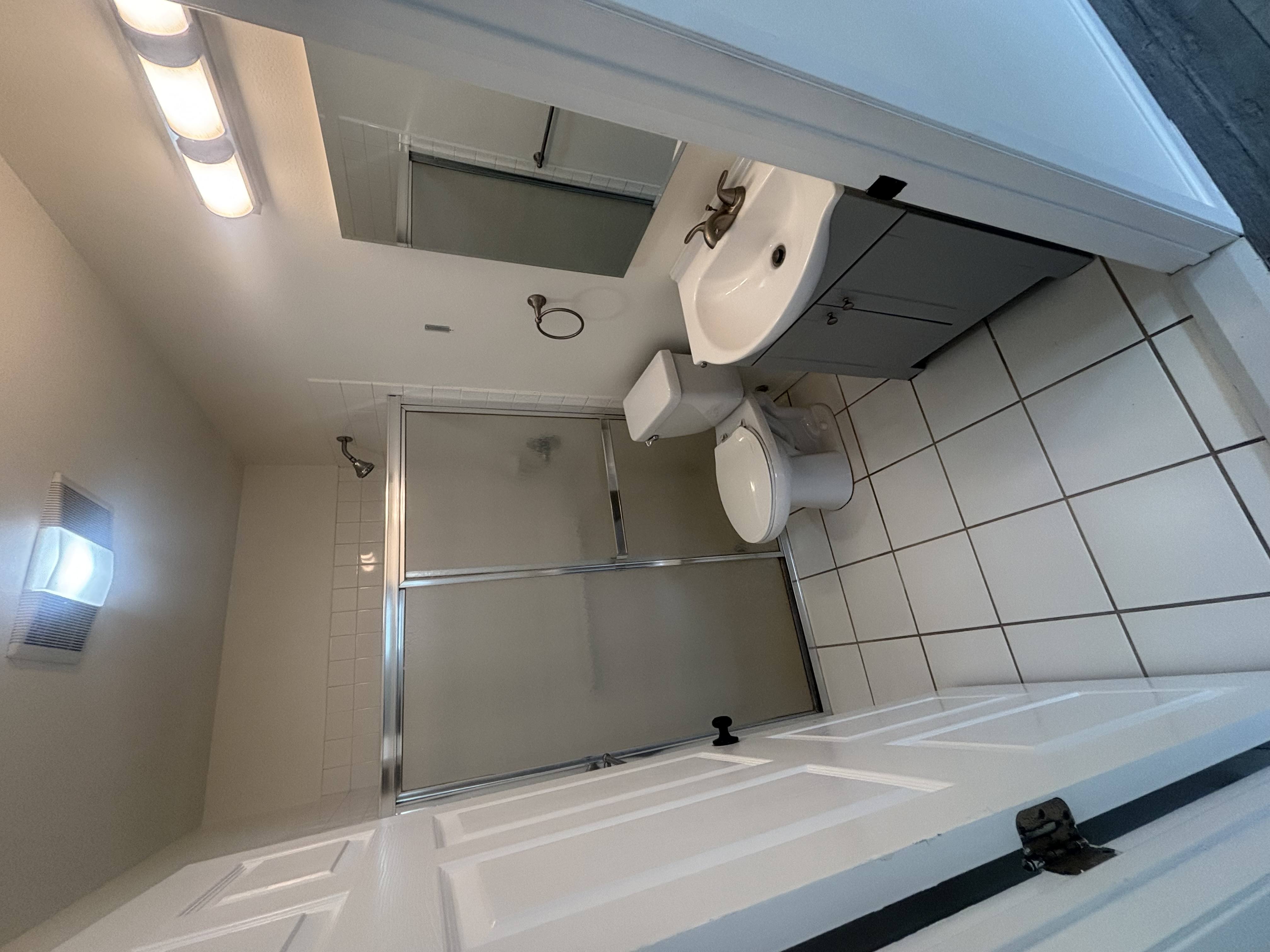 A white bathroom with a toilet, sink, and shower.
