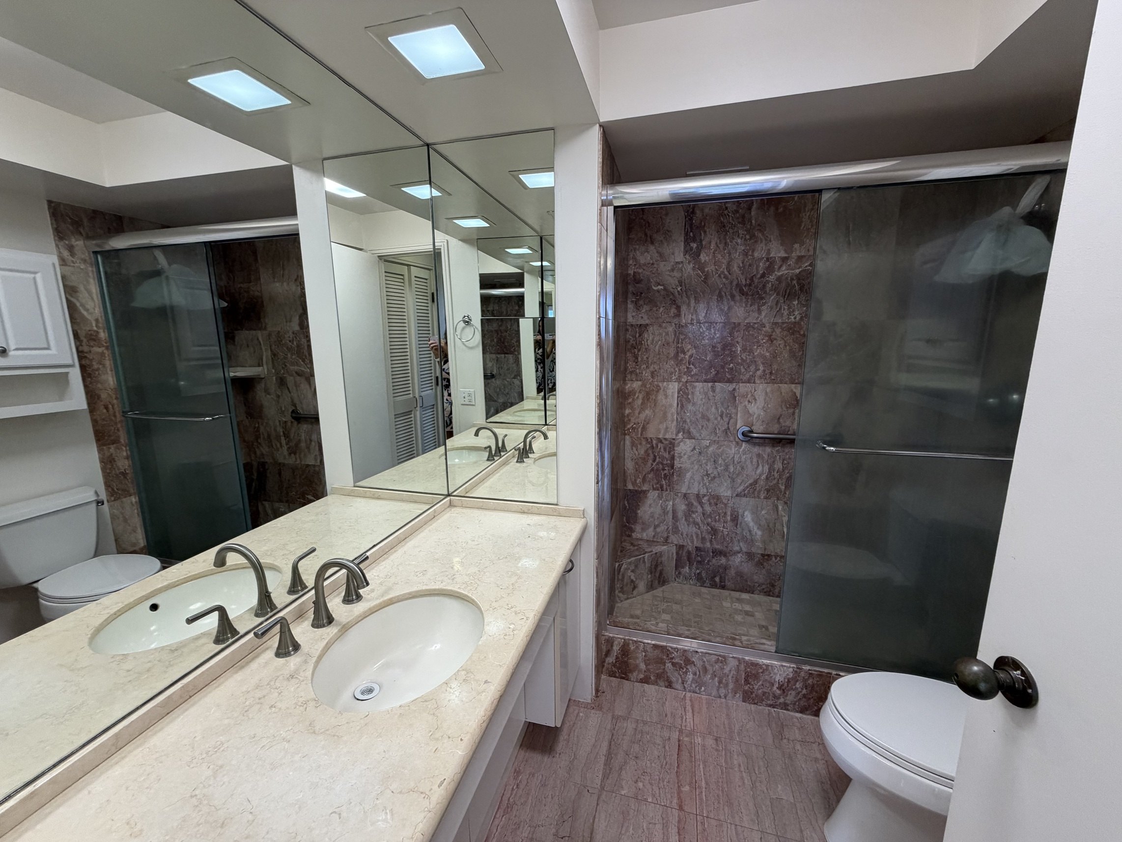 A bathroom with a marble countertop and a walk-in shower.