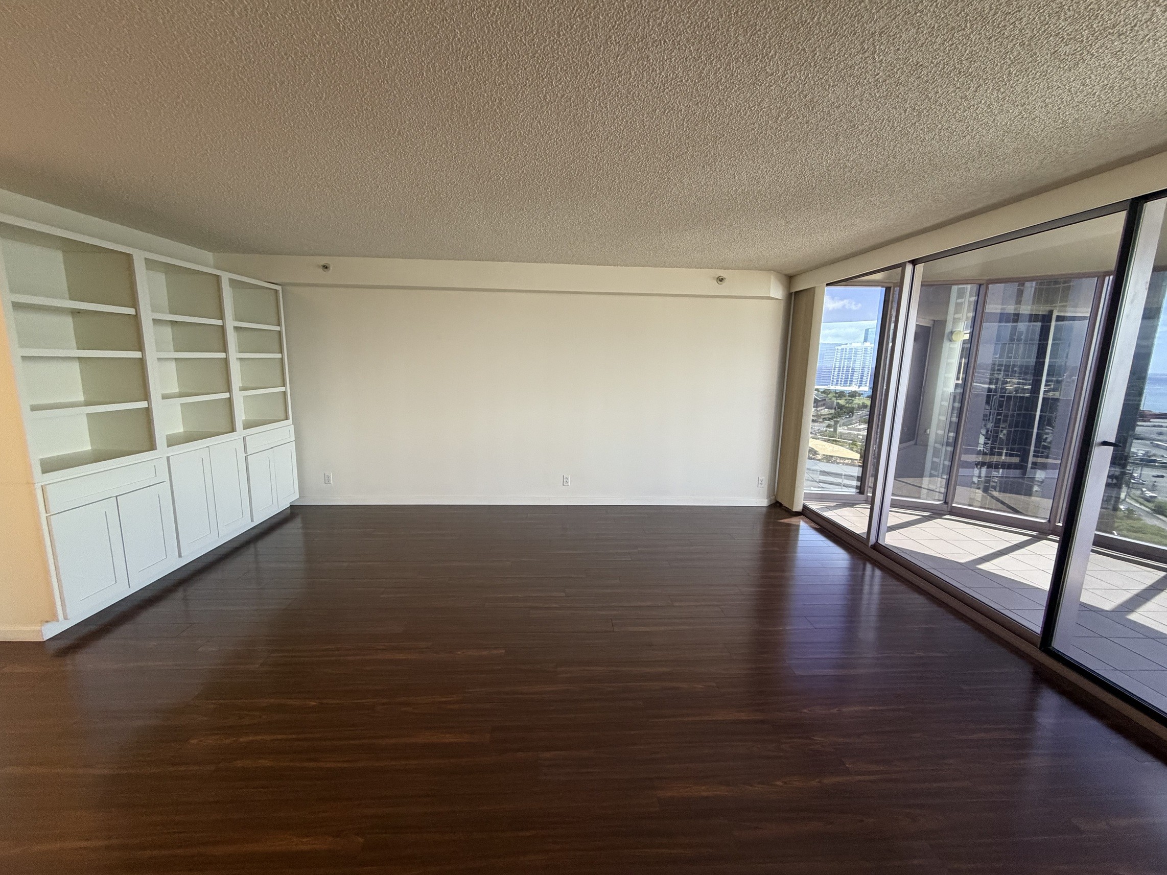 A room with wooden floors and a large window overlooking a cityscape.