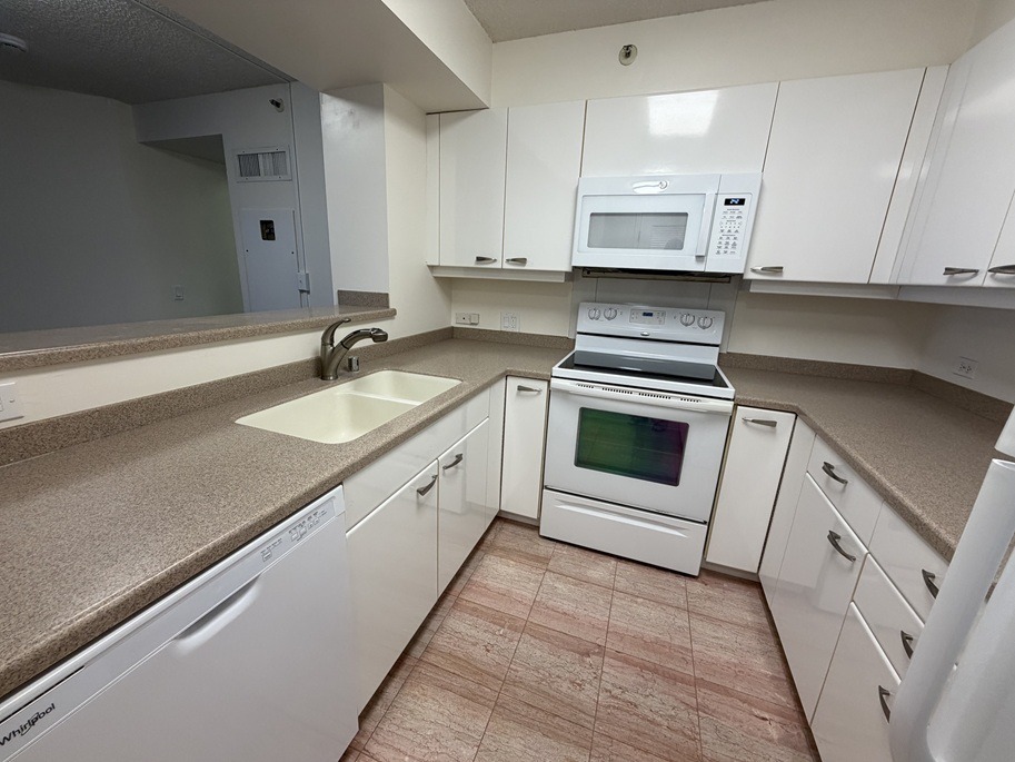 A kitchen with white appliances and brown countertops.
