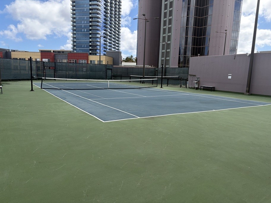 A tennis court with a net and tall buildings in the background.