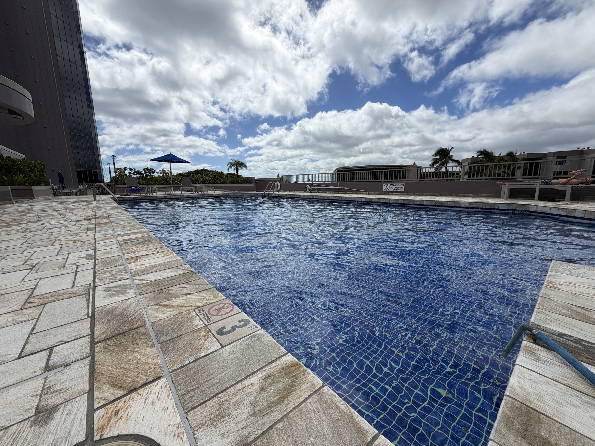 A large swimming pool with a tiled edge and a wooden deck.