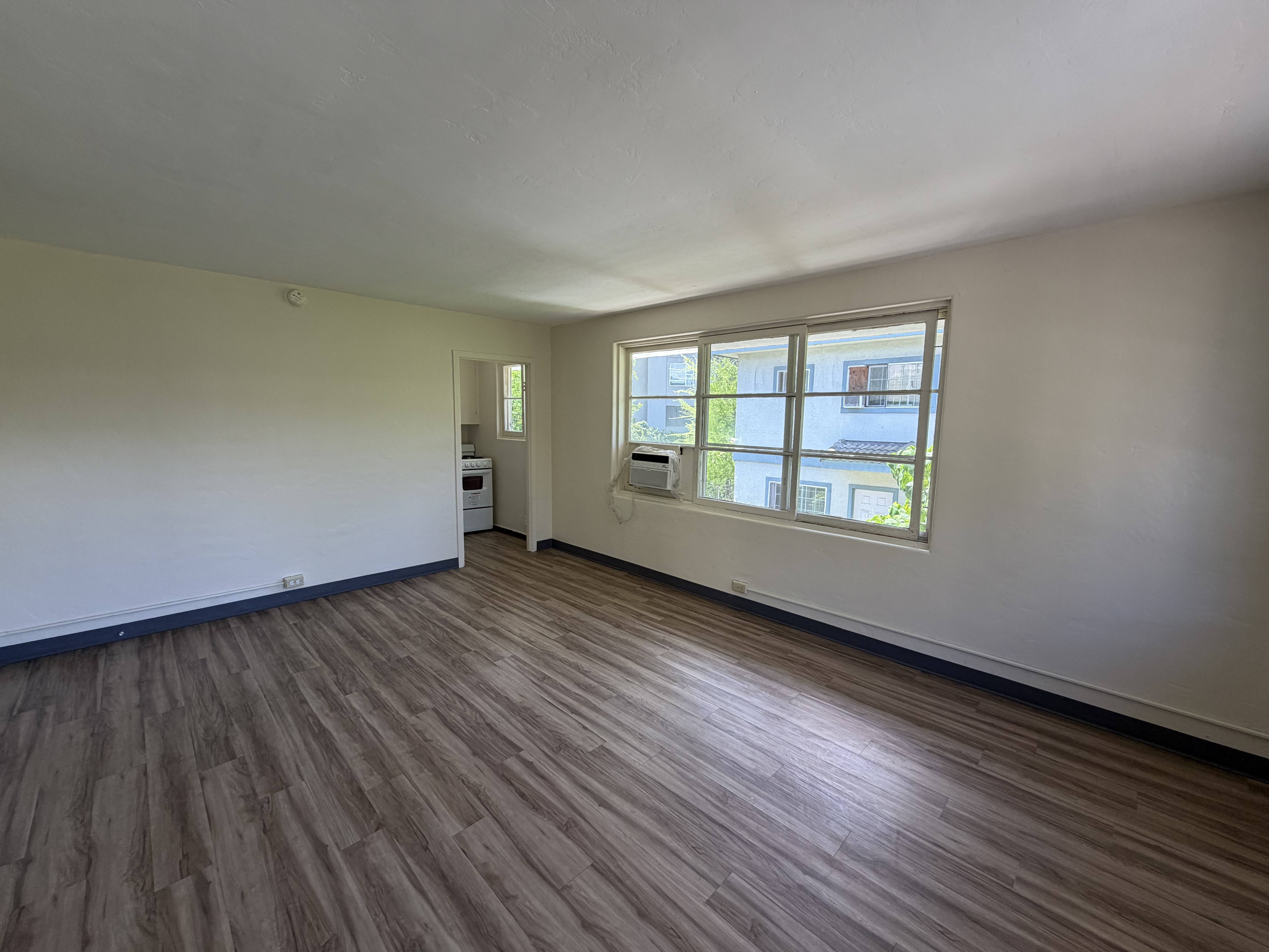 A room with wooden flooring and a window.