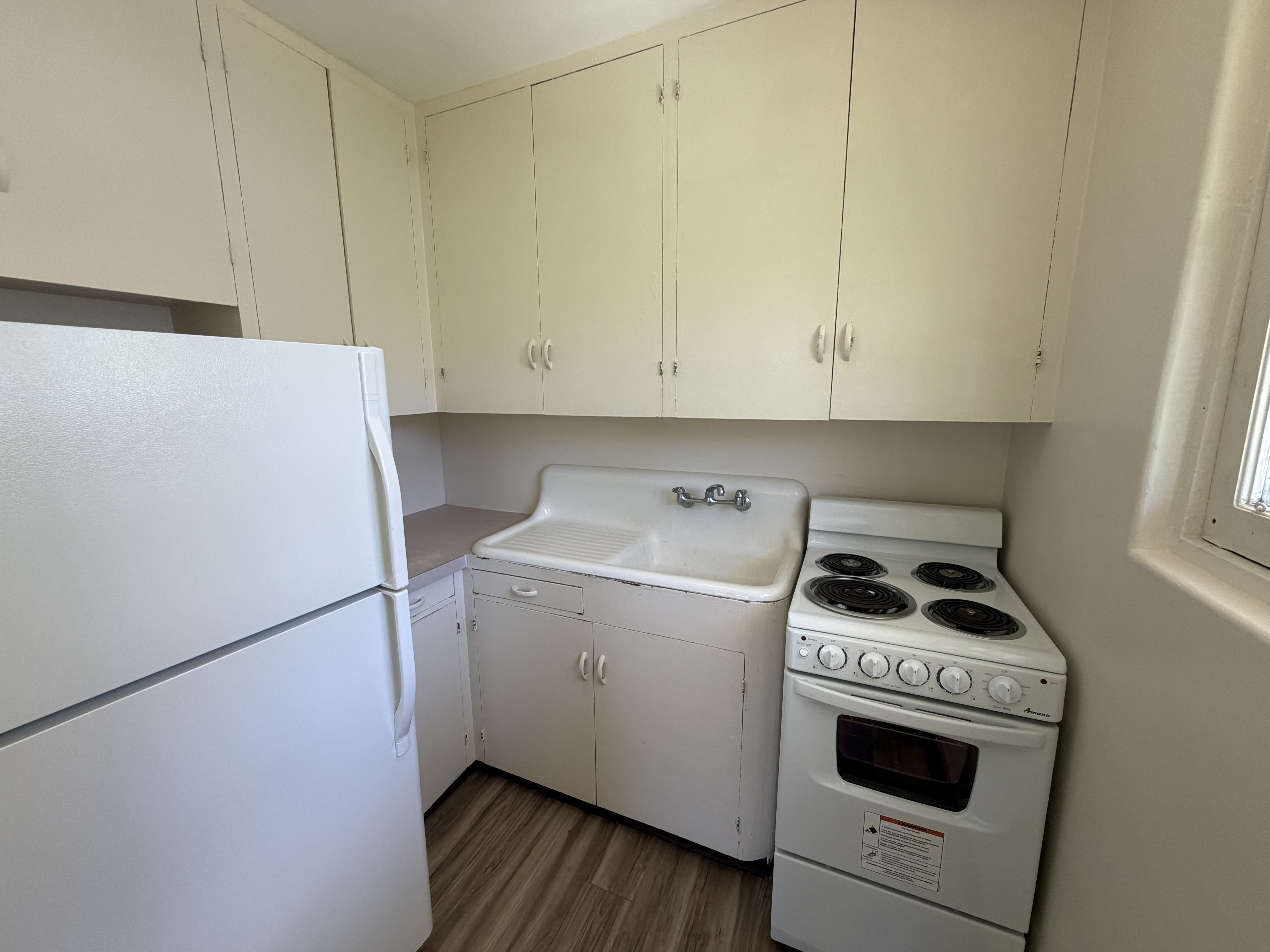 A white fridge and oven in a kitchen with white cabinets.