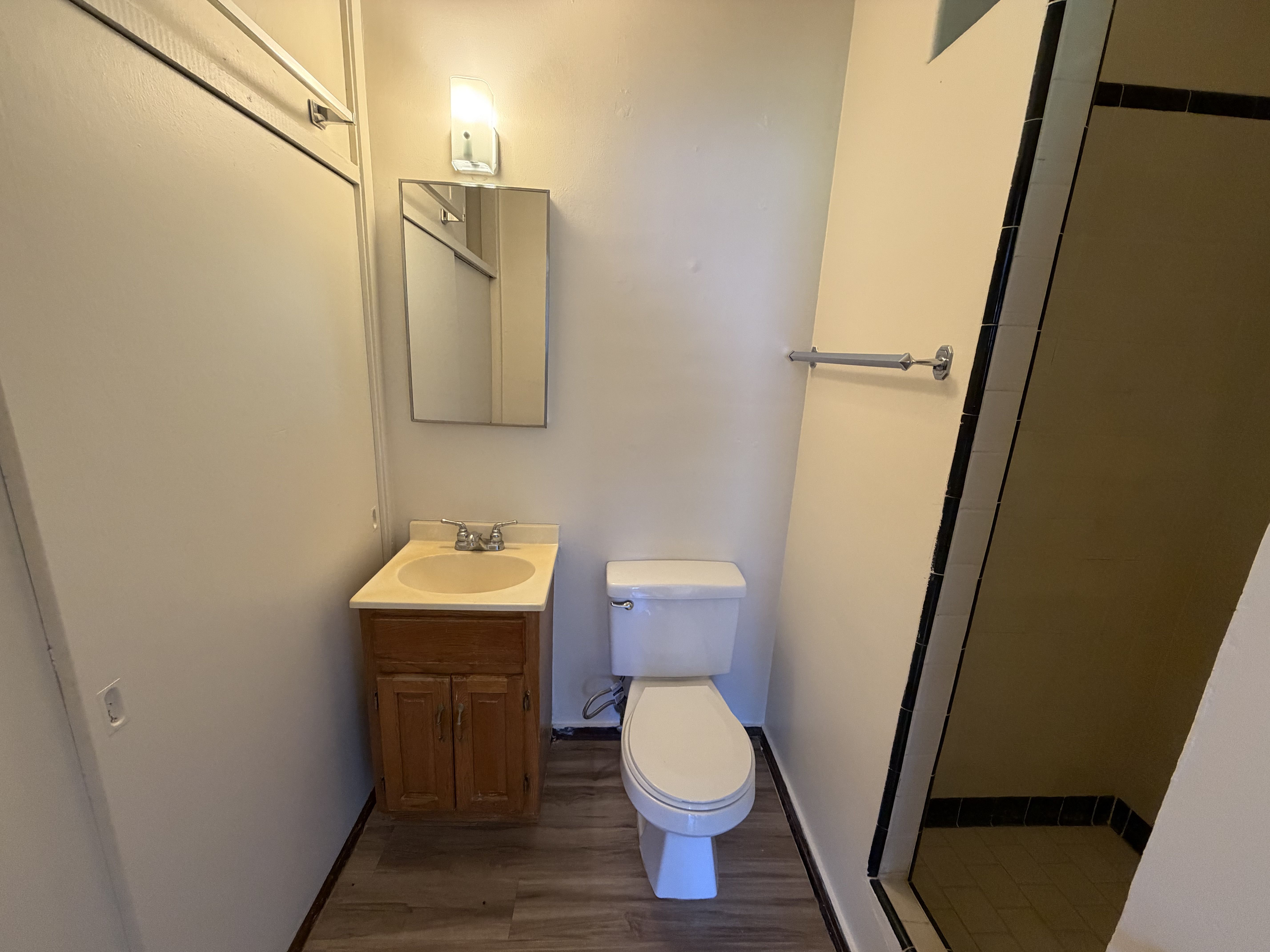 A bathroom with a toilet, sink, and mirror.