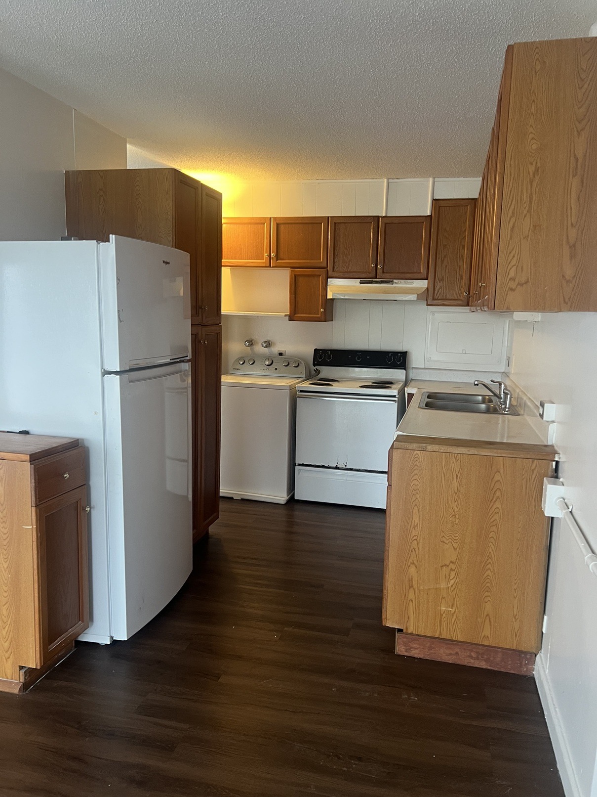 A kitchen with white appliances and wooden cabinets.