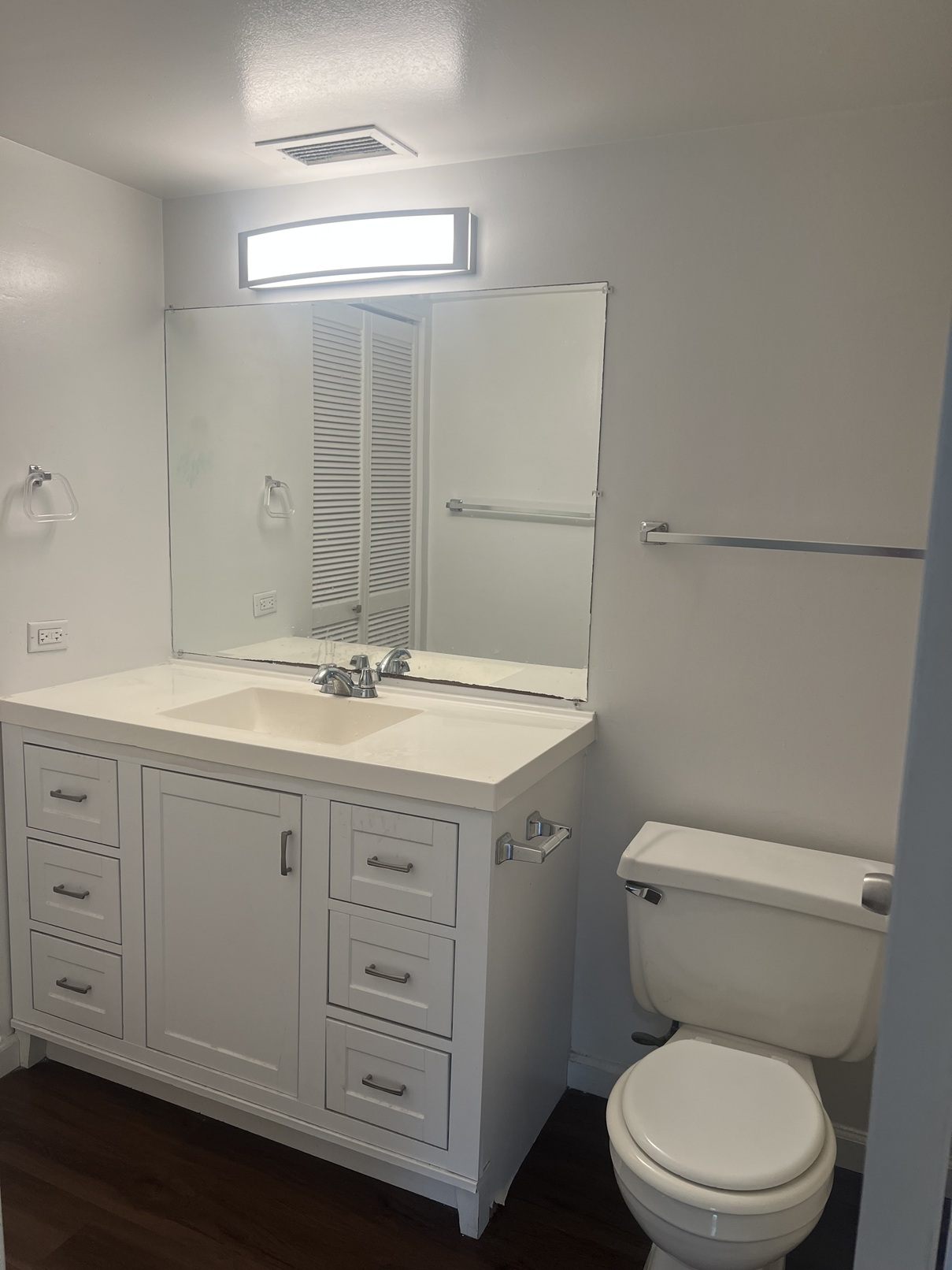 A white bathroom with a toilet, sink, and mirror.