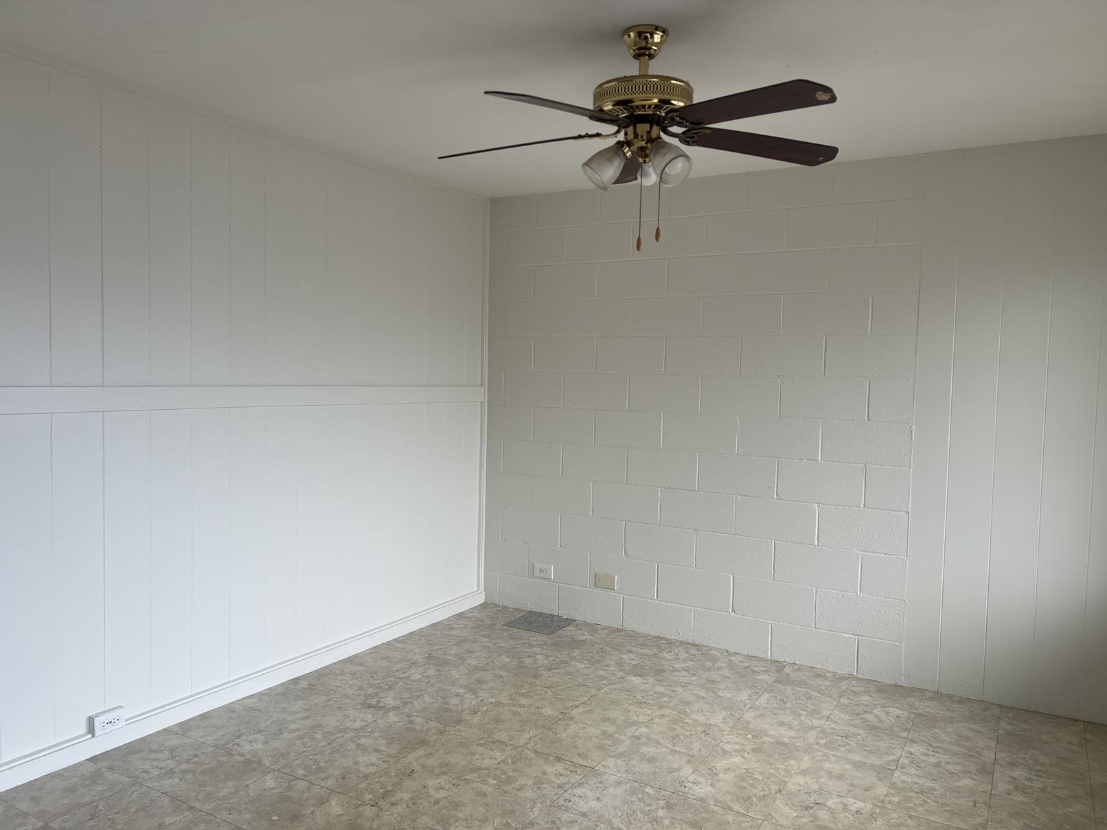 A room with a ceiling fan and a tiled wall.