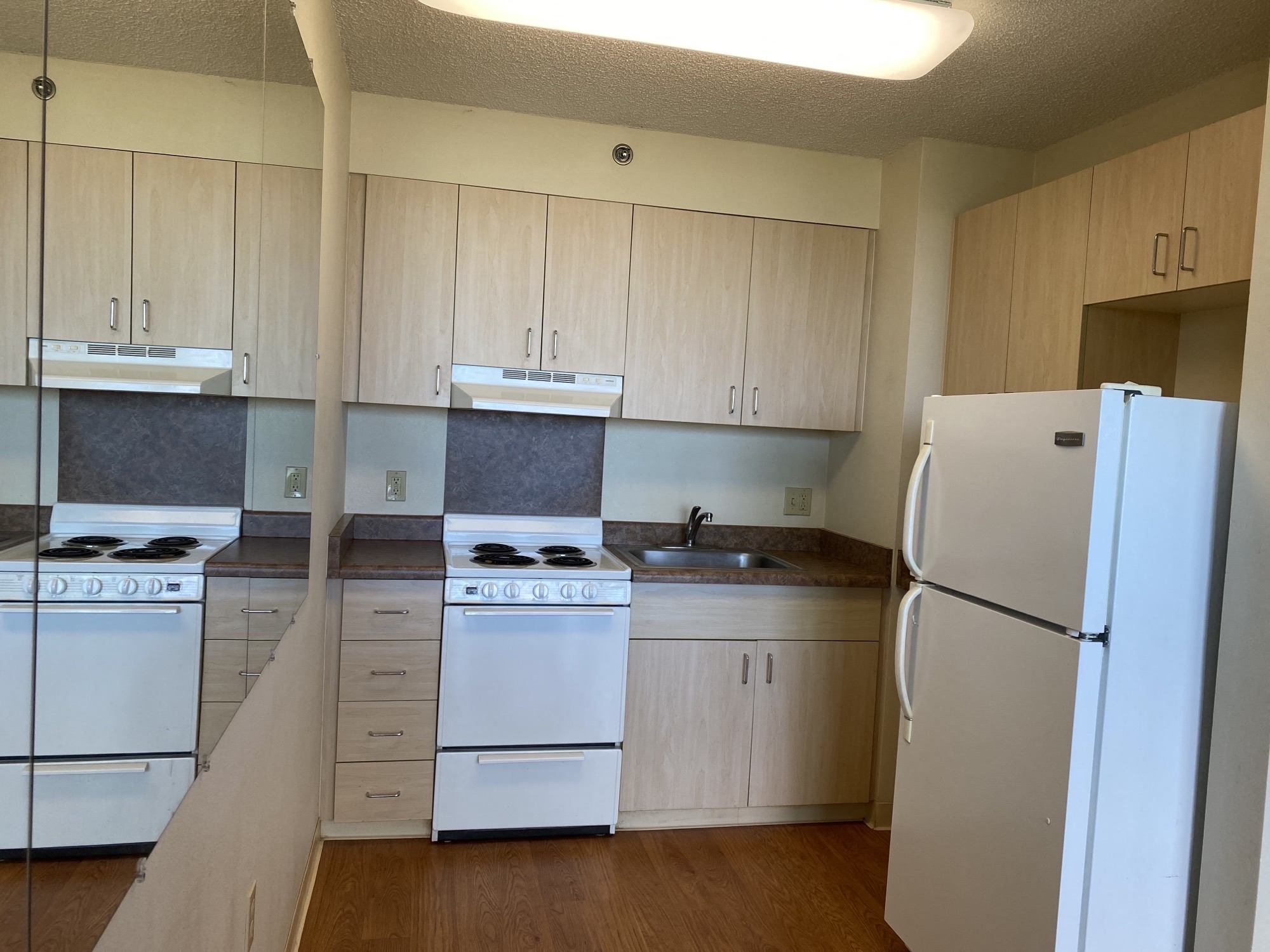 an empty kitchen with white appliances and wooden cabinets